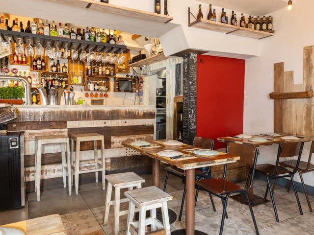 Balcão do bar com prateleiras de garrafas e uma parede vermelha